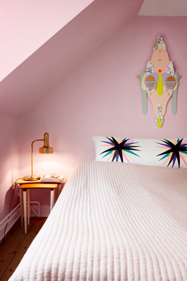 rosa farvet soveværelse med multifarve collage art maske hængende